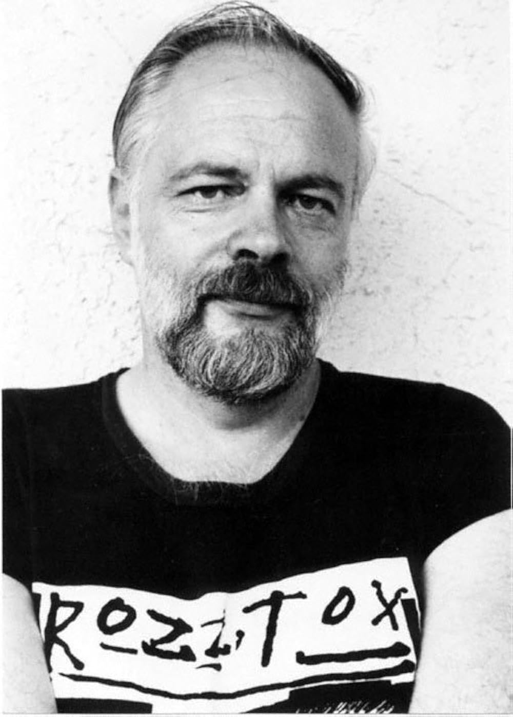 Black-and-white portrait of a man with short hair and a beard (the author), wearing a T-shirt with bold text, looking at the camera.